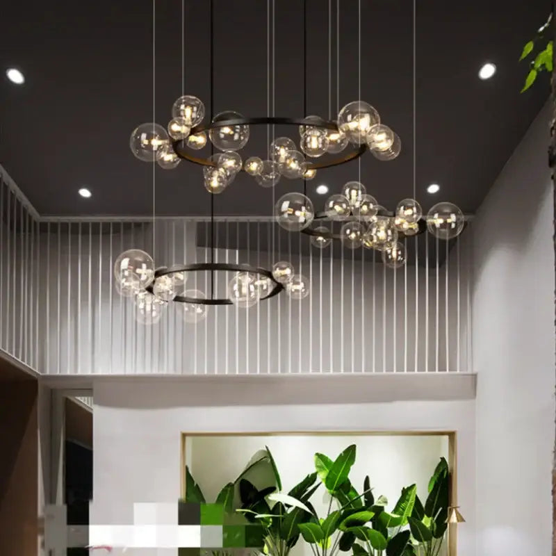 Modern black glass globe pendant light fixture with black metal rings and hanging wires for dining room lighting