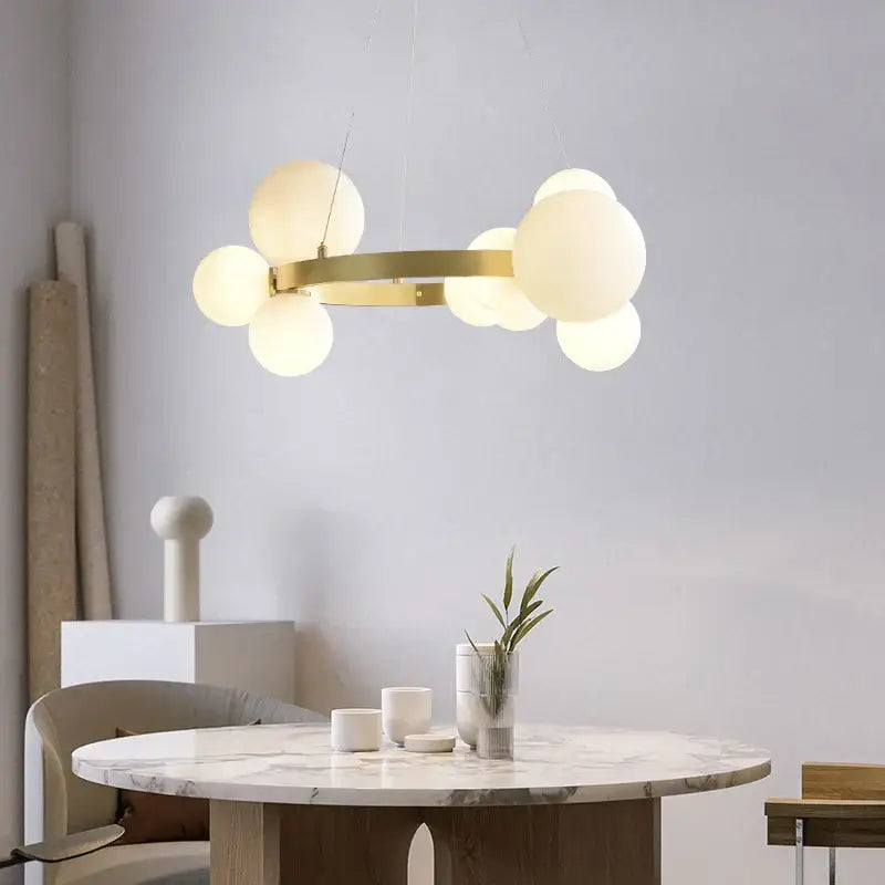 Modern gold-toned pendant light fixture with frosted glass globe lights arranged in a circular cluster for dining room