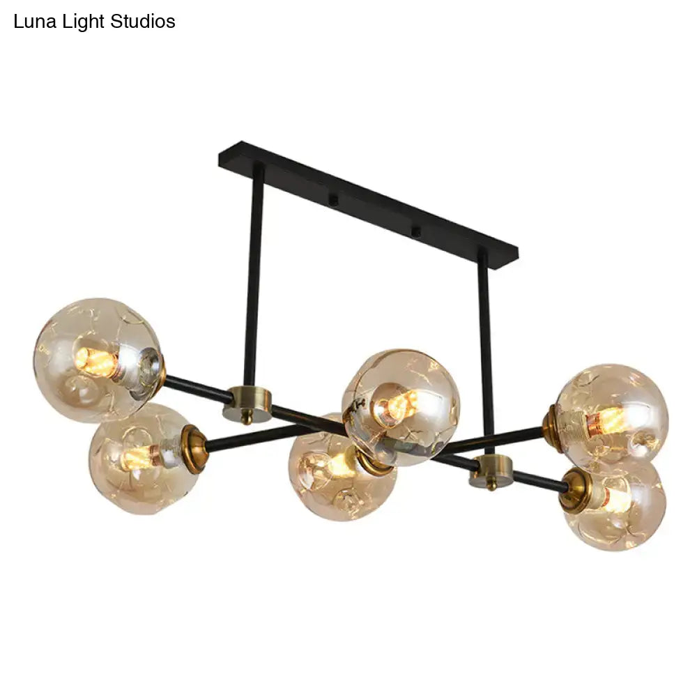 Modern black island pendant light with six amber stained glass globe bulbs and brass accents for dining room use