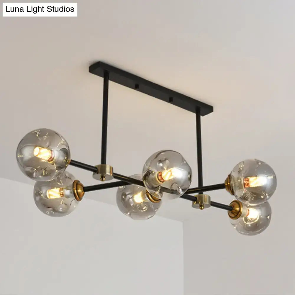 Modern black glass island pendant light featuring brass accents and six clear glass globe bulbs for dining room use