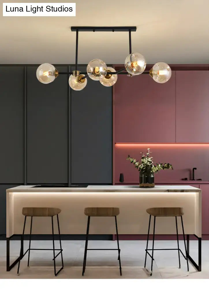 Modern black glass island pendant light with six clear globe bulbs and brass accents for dining room illumination