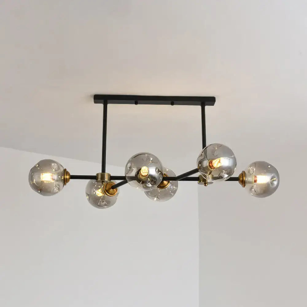 Modern black island pendant light with six clear glass globe bulbs and brass accents for dining room lighting
