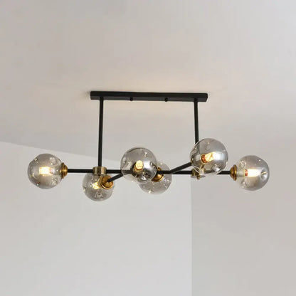 Modern black island pendant light with six clear glass globe bulbs and brass accents for dining room lighting
