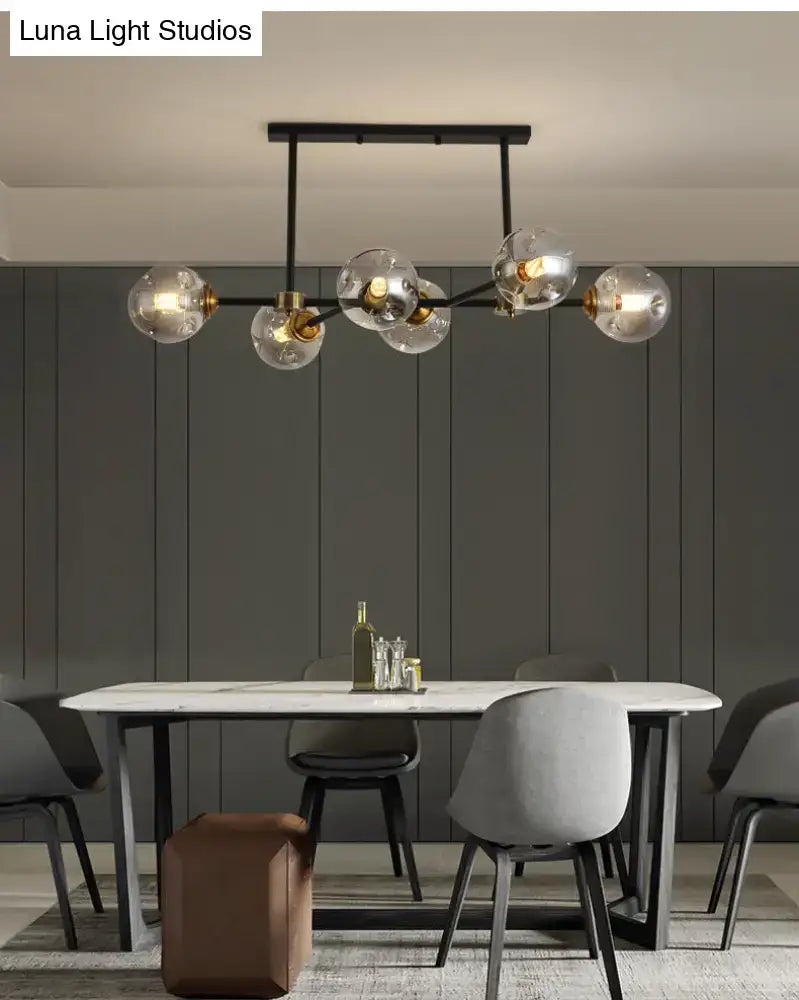 Modern black island pendant light with brass accents and clear glass globe bulbs for dining room lighting