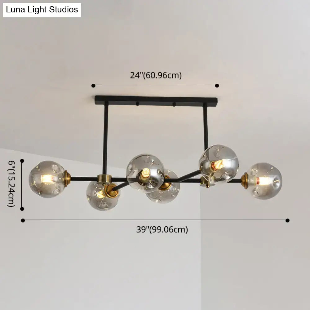 Modern black metal island pendant light with five clear glass globes and brass accents for dining room lighting