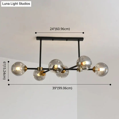 Modern black metal island pendant light with five clear glass globes and brass accents for dining room lighting