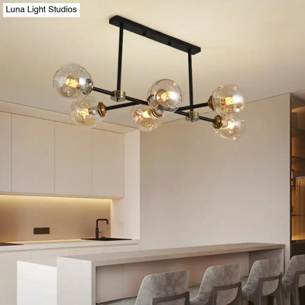 Modern black island pendant light with six clear glass globe bulbs and brass accents for dining room use