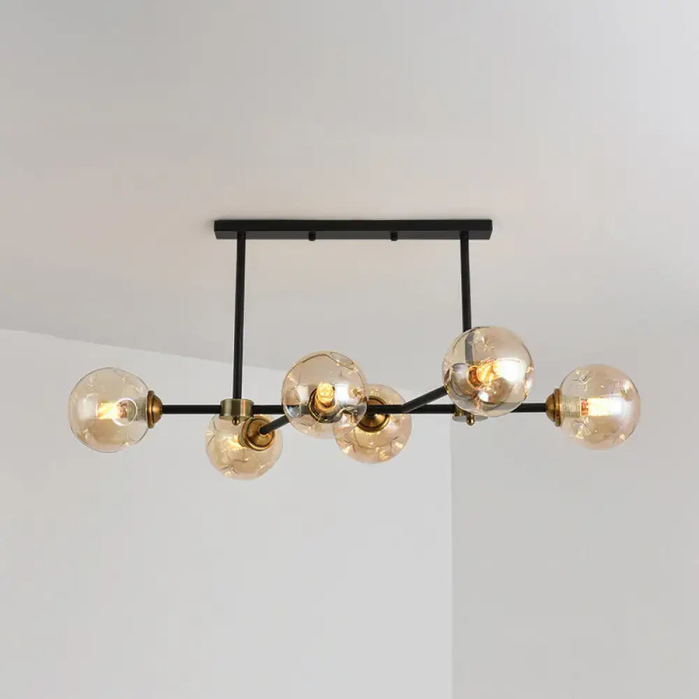 Modern black island pendant light with six amber glass globes and brass accents for dining room or kitchen island lighting