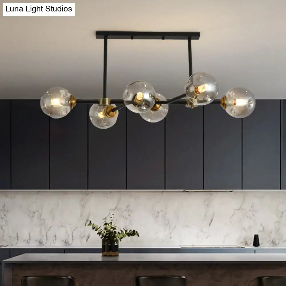 Modern black island pendant light with five clear glass globe bulbs and brass accents for dining room lighting