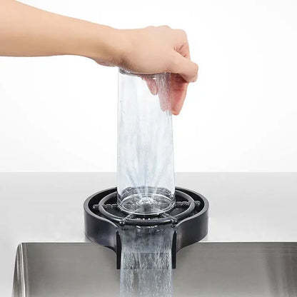 Clear glass pitcher being rinsed in a modern black glass rinser sink drip tray for automatic cup washing