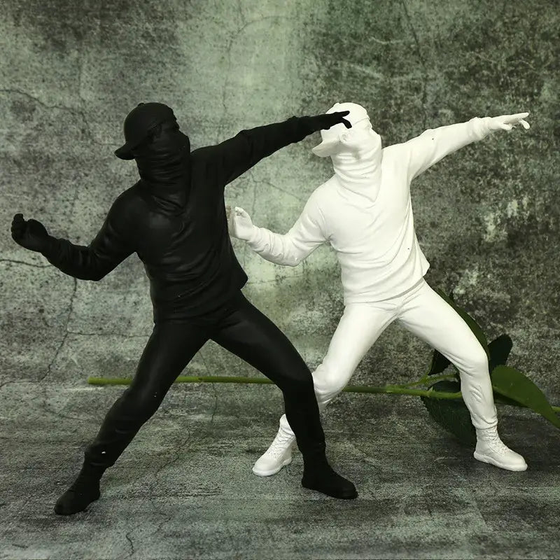 Modern black glossy bansky flower thrower sculpture featuring black and white plastic figurines in dynamic poses