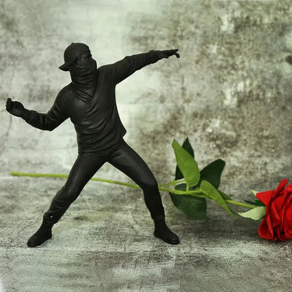 Black plastic bansky flower thrower sculpture in a dynamic pose with glossy finish for modern office decor