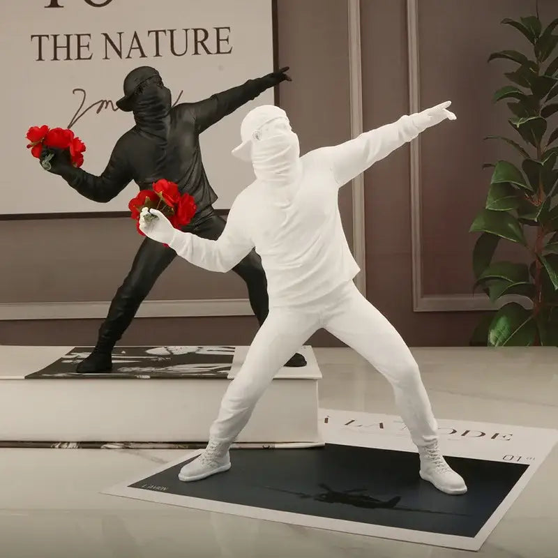 Modern black glossy bansky flower thrower sculpture featuring white and black dancer figurines holding red rose bouquets