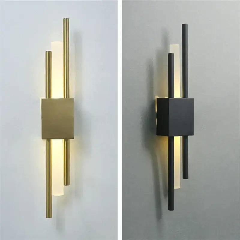 Modern black and gold acrylic pipe wall lamp with brushed brass base and frosted glass diffusers emitting warm light