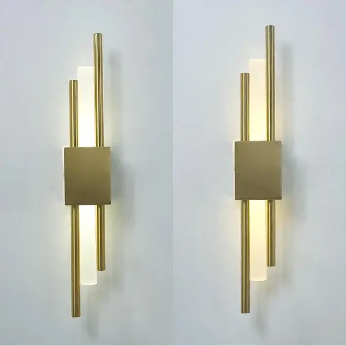 Modern black and gold acrylic pipe wall lamp with vertical gold acrylic pipe rods and frosted glass panels emitting warm light