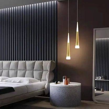 Two sleek gold-toned aluminum cord pendant lights with tapered shades for modern bedroom lighting