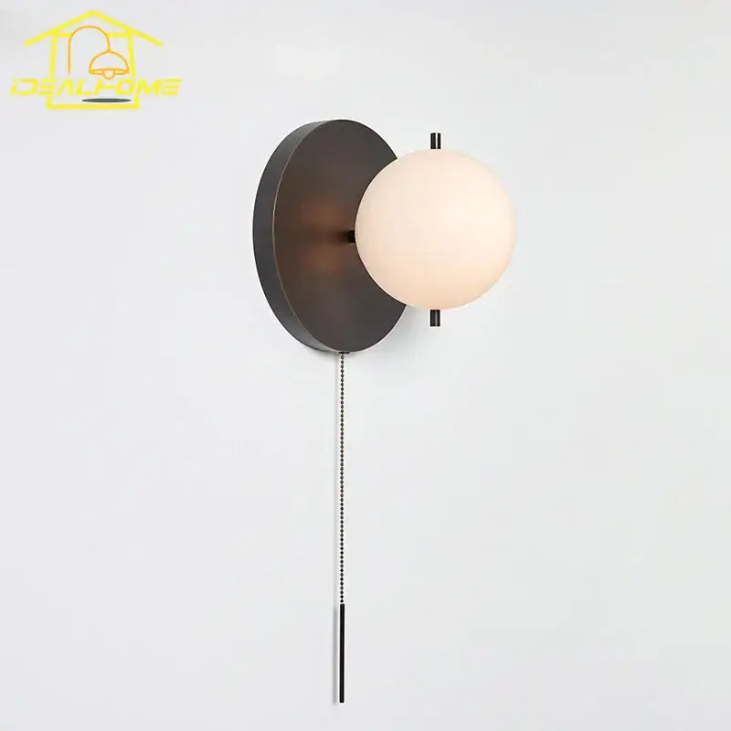 Modern black gold ball wall lamp with a matte circular base and off-white glass globe by decorbites black gold