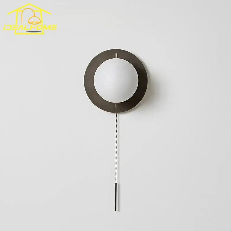Modern wall lamp with matte black circular frame frosted glass globe and sleek chain pull decorbites black gold ball design