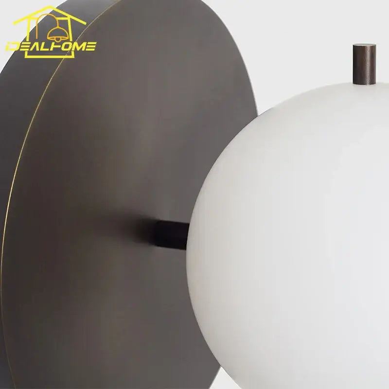 A sleek matte dark bronze wall lamp with a smooth white glass shade decorbites black gold ball bedroom sconce
