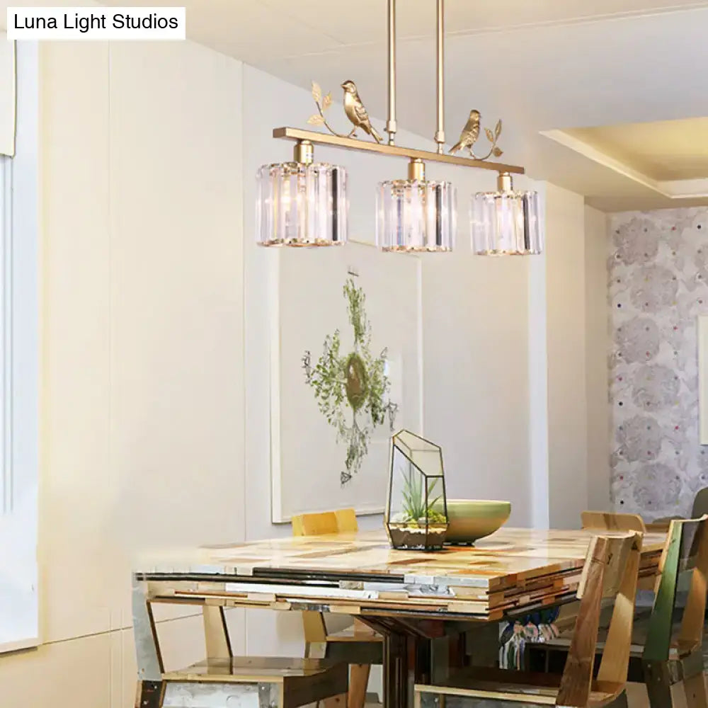 Brass-finished pendant light with three clear crystal glass shades and decorative bird motifs in black gold accents