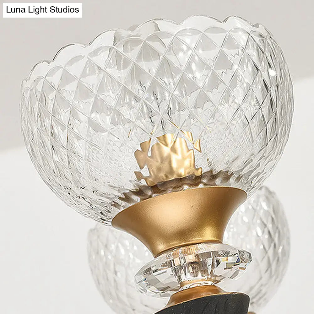 Modern black and gold branch sconce featuring a clear prismatic glass shade with a gold-toned metal base and accents