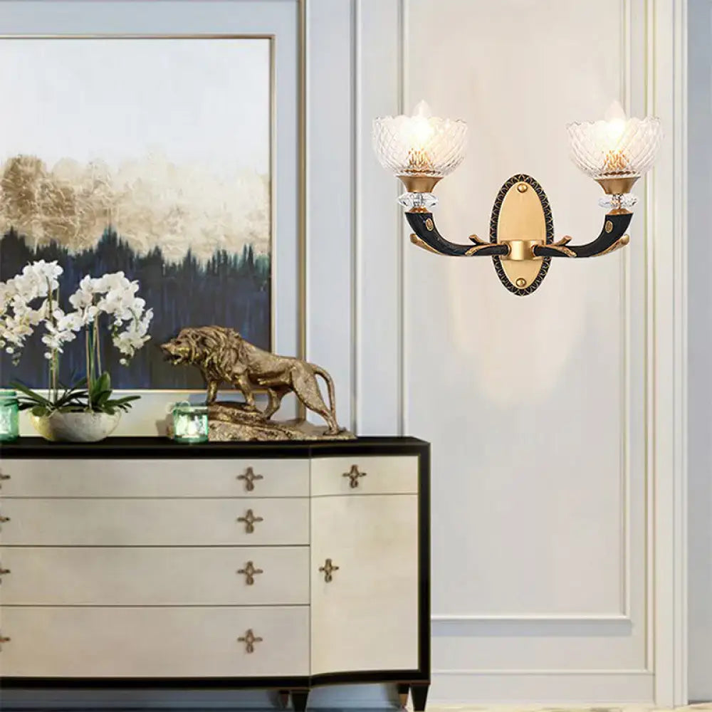 Modern black and gold metal black sconce with clear prismatic glass shade and black horn-like arms for bedroom use
