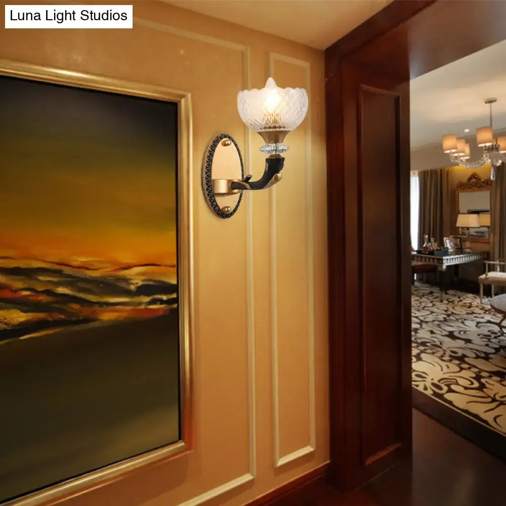 Elegant metal black sconce with gold-toned frame and frosted clear prismatic glass shade for modern bedroom use