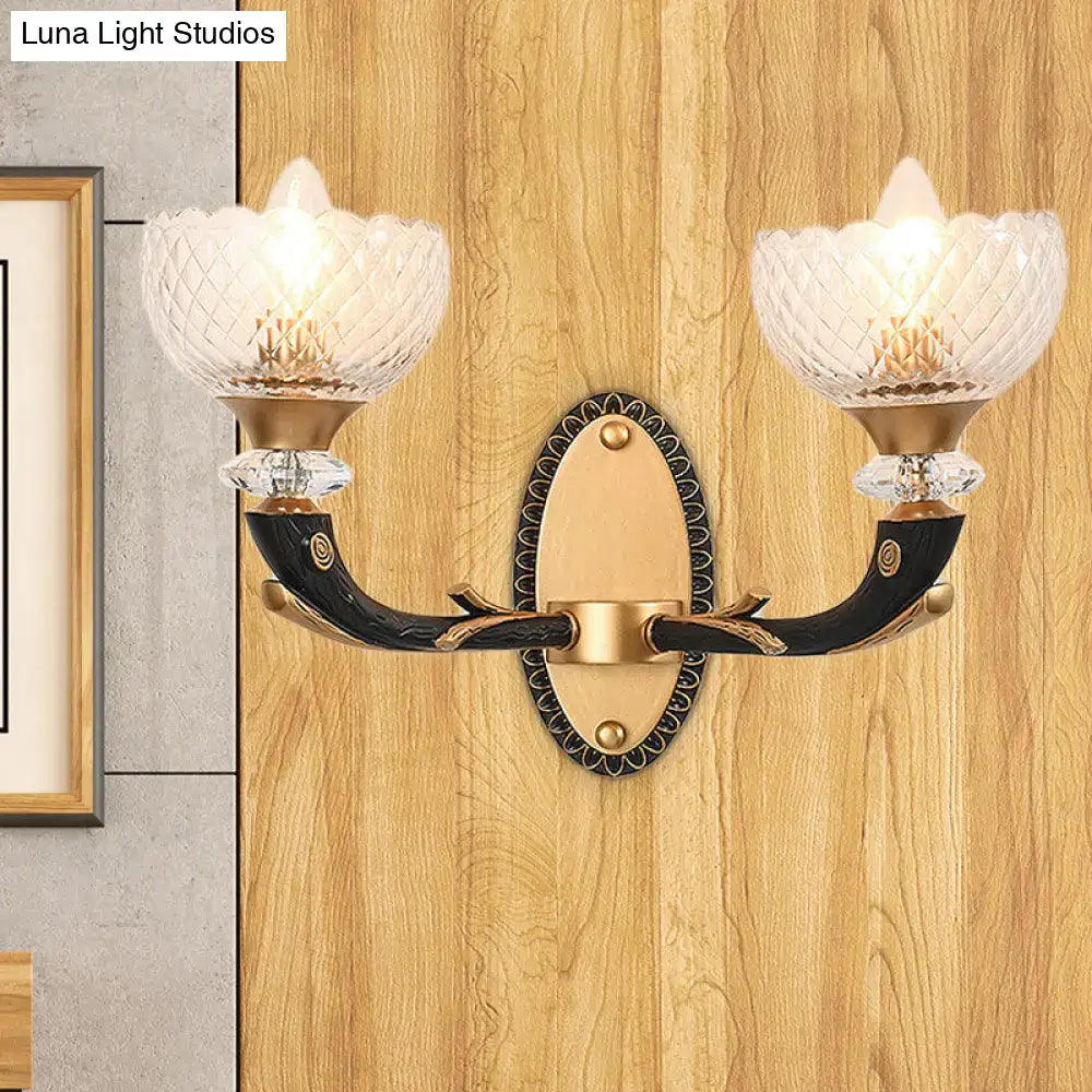 Elegant metal black sconce with gold accents and clear prismatic glass shade for modern bedroom lighting