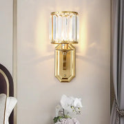 Modern black gold wall sconce with clear crystal cylindrical shade and octagonal base ideal for bedroom fixture height