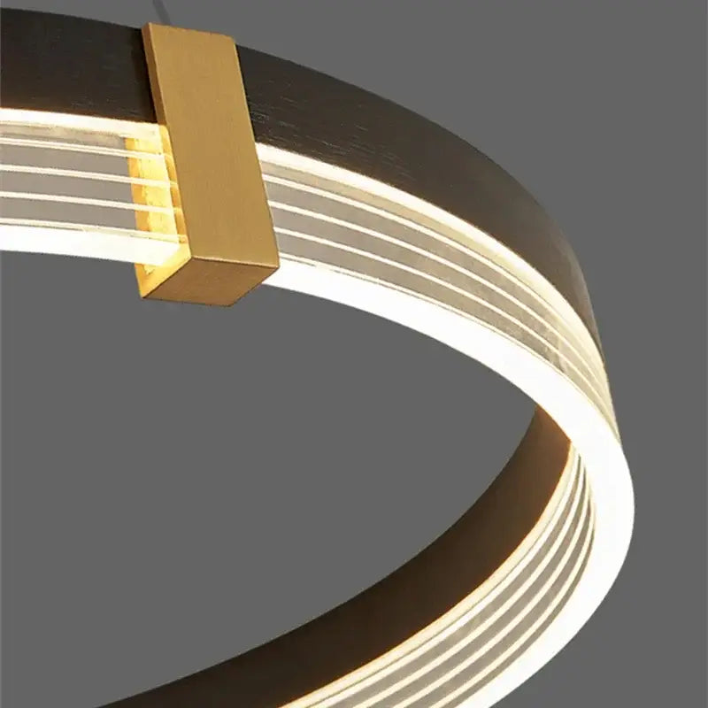 Modern black and gold decorbites circle chandelier with sleek curved frame and warm LED strips for dining room lighting