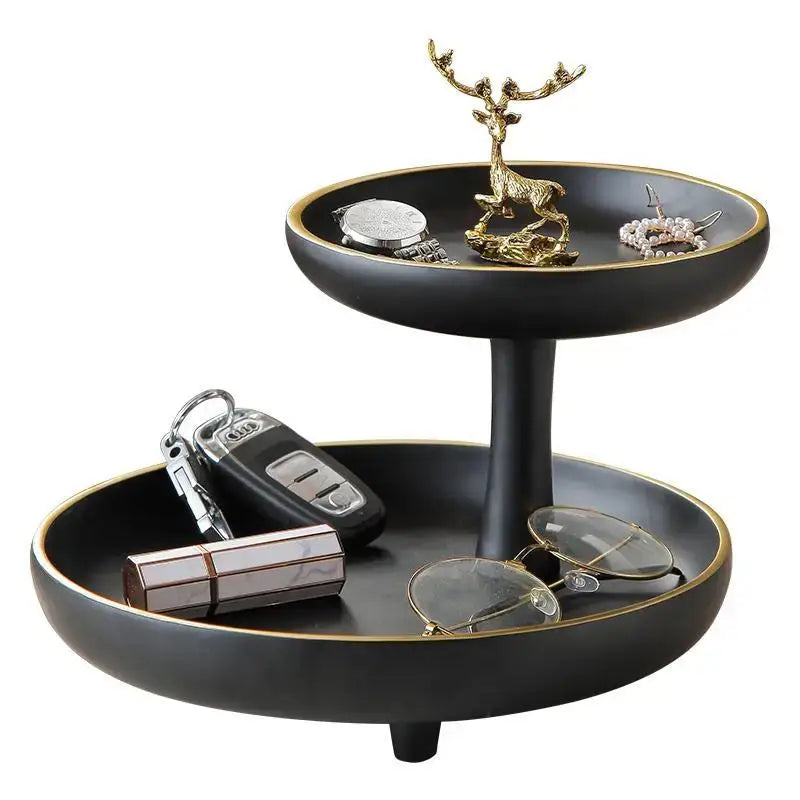 Modern black and gold two-tiered coffee table tray with central pedestal holding keys glasses and jewelry