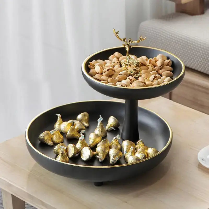 Modern black and gold two-tiered coffee table tray with golden deer centerpiece holding pistachios and chocolates