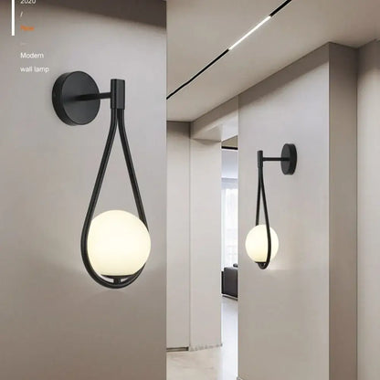 Modern black and gold decorbites glass ball led wall lamp with a sleek teardrop frame and frosted glass globe for bedroom decor