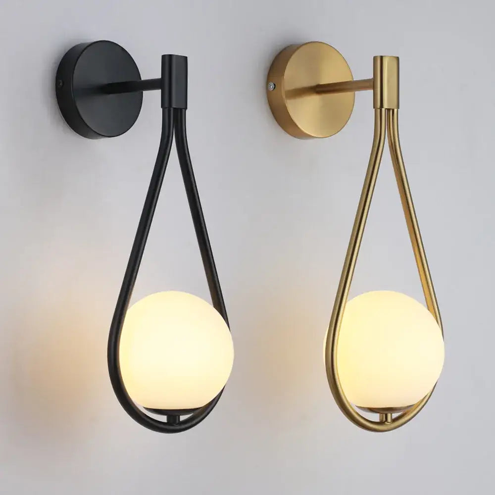 Modern black and gold wall lamp featuring a teardrop metal frame with a warm glowing decorbites glass ball led bulb