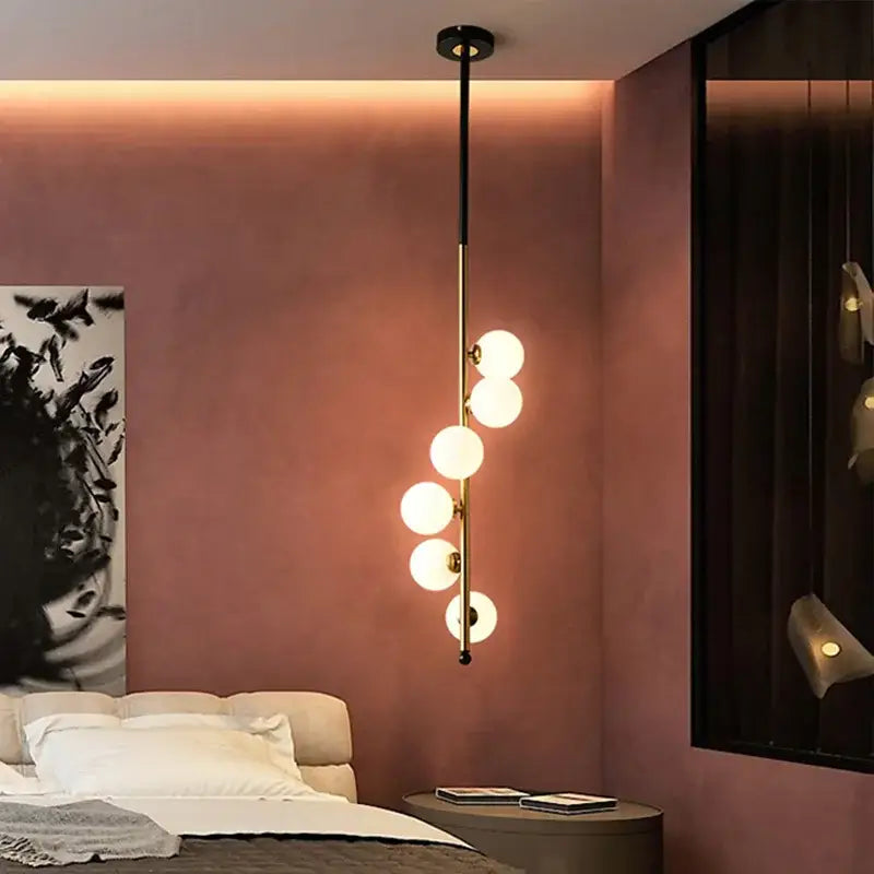 Modern black and gold glass ball pendant lights with five glowing white bulbs in a sleek vertical dining room design