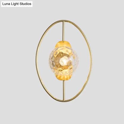 Modern black and gold wall lamp featuring a gold-toned oval frame and a textured translucent white glass globe fixture type