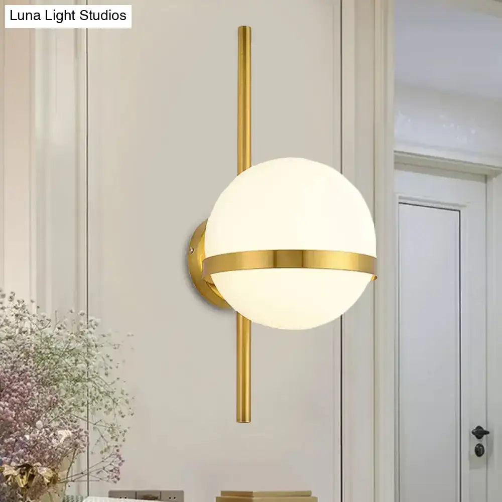 Modern black gold glass shade wall sconce with gold-toned spherical frosted globe and horizontal accent band for bedroom light