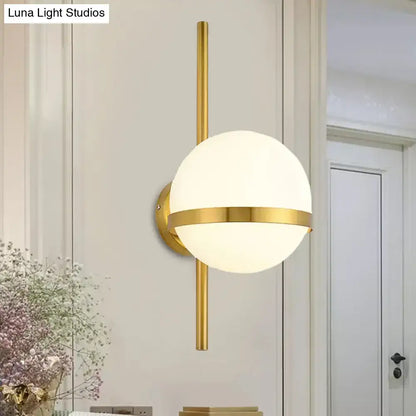 Modern black gold glass shade wall sconce with gold-toned spherical frosted globe and horizontal accent band for bedroom light