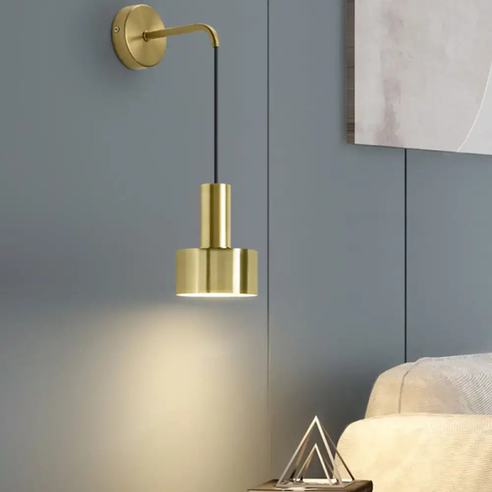 Gold-finished minimalist wall lamp with sleek curved arm and cylindrical shade for modern bedroom reading light