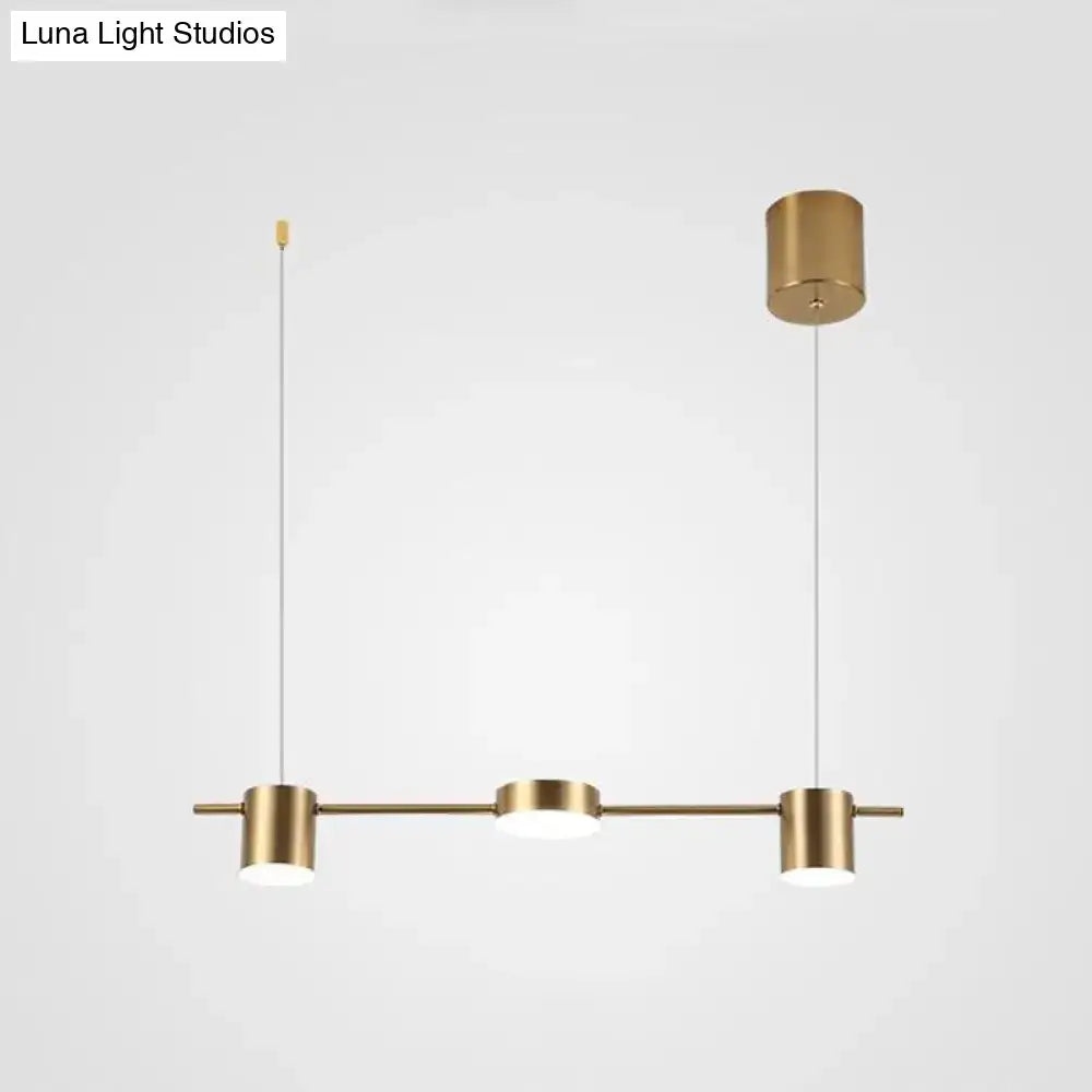 Modern black gold ceiling light fixture with brass-finished pendant light and three cylindrical fixtures for kitchen island
