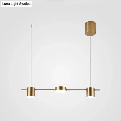 Modern black gold ceiling light fixture with brass-finished pendant light and three cylindrical fixtures for kitchen island