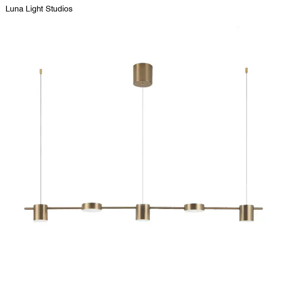 Modern black gold ceiling light fixture with brass-finished pendant and four cylindrical fixtures for kitchen island