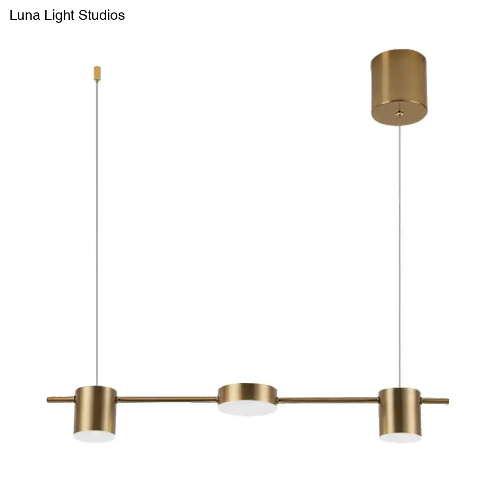 Modern black gold ceiling light fixture with brass finish, three cylindrical shades, and frosted glass diffuser for kitchen island