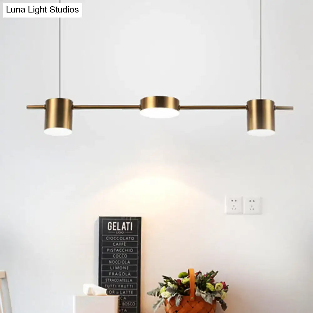 Modern black gold ceiling light fixture with brass-finished pendant and three cylindrical shades for kitchen island