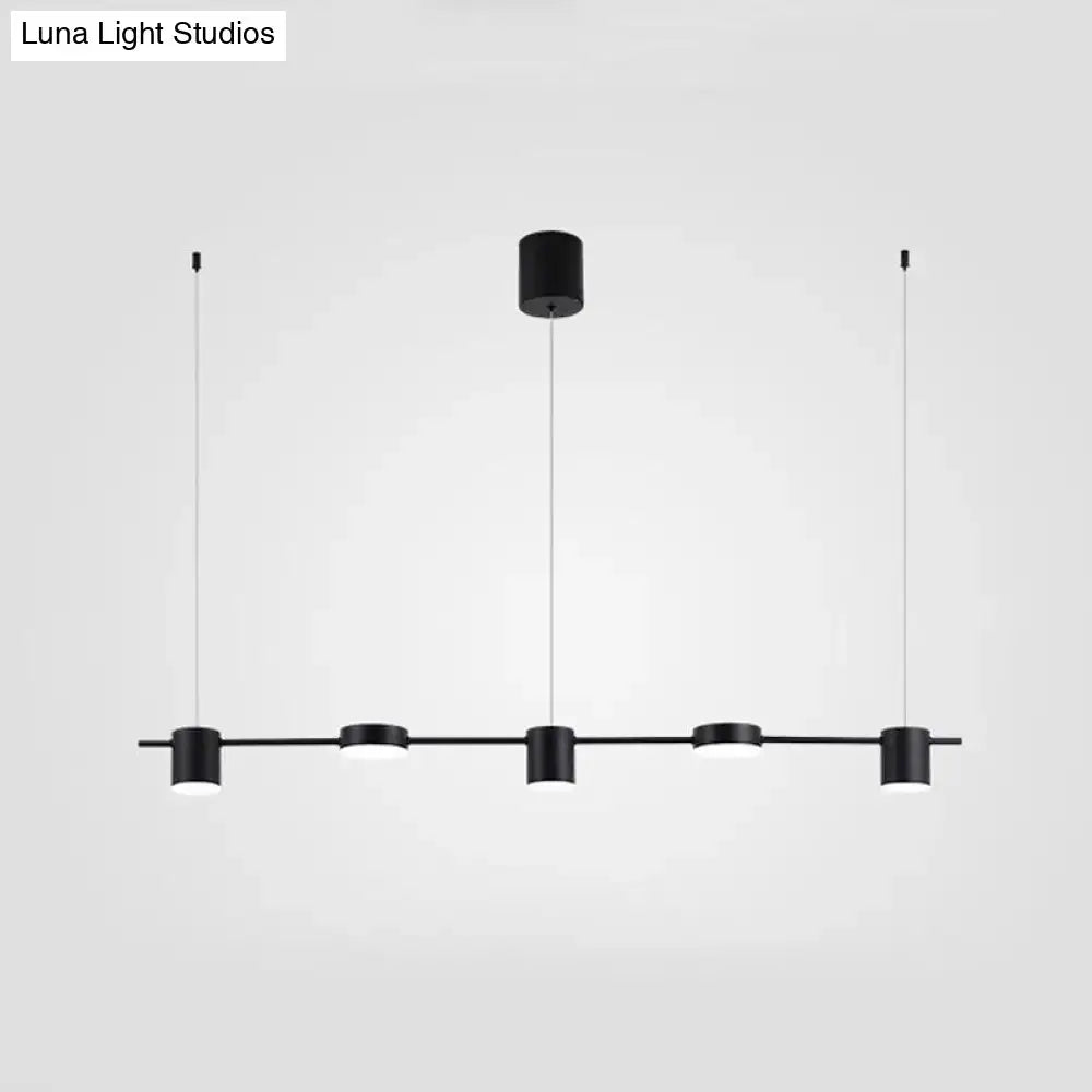 Modern black and gold ceiling light fixture featuring four minimalist cylindrical pendants for kitchen island lighting