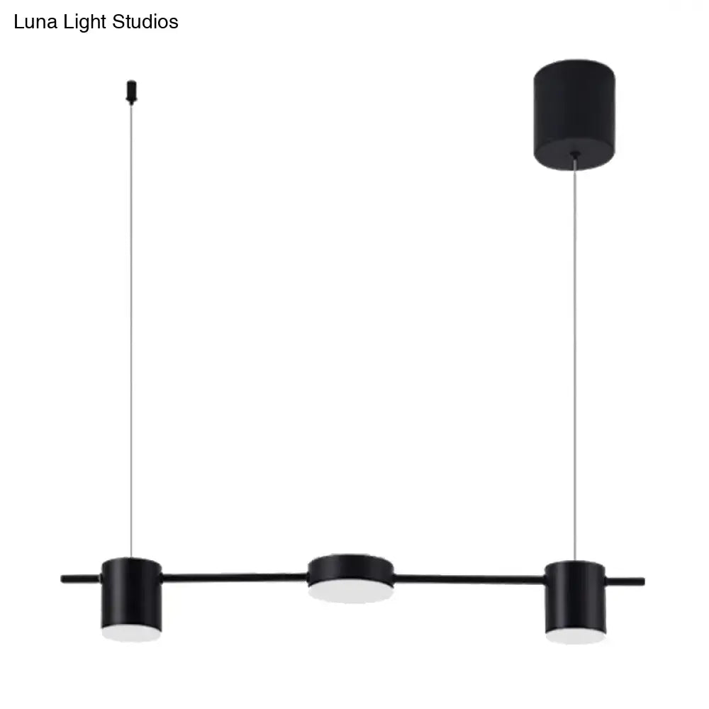 Modern black gold ceiling light fixture with three black cylindrical pendant lights suspended by thin cords