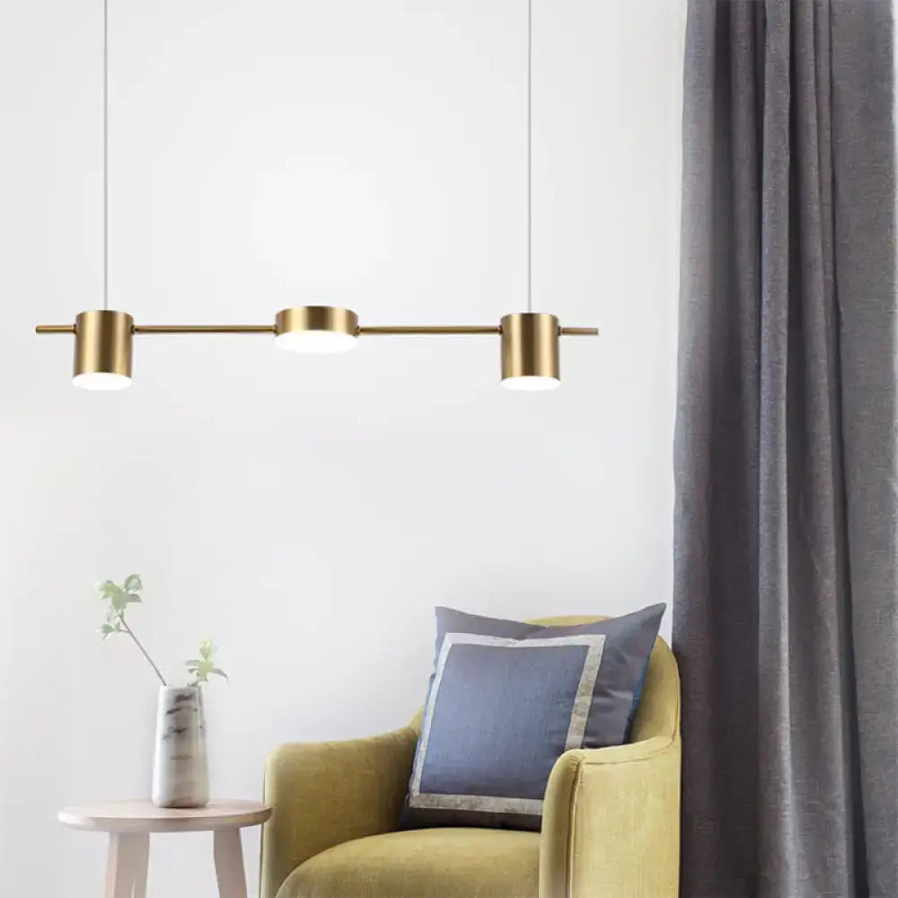 Modern black gold ceiling light fixture with three gold-toned cylindrical bulbs on a sleek horizontal bar for kitchen islands