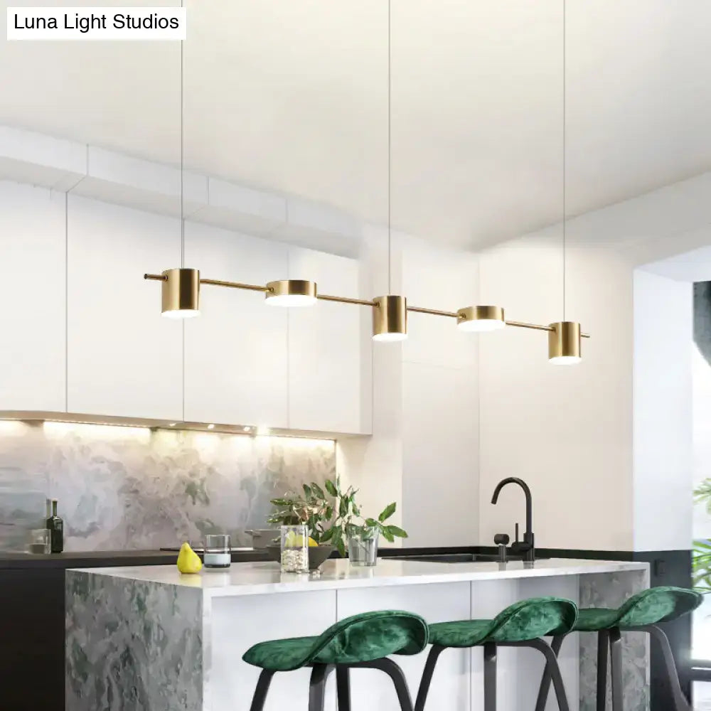 Modern black gold ceiling light fixture with gold-toned linear pendant and cylindrical shades above kitchen island