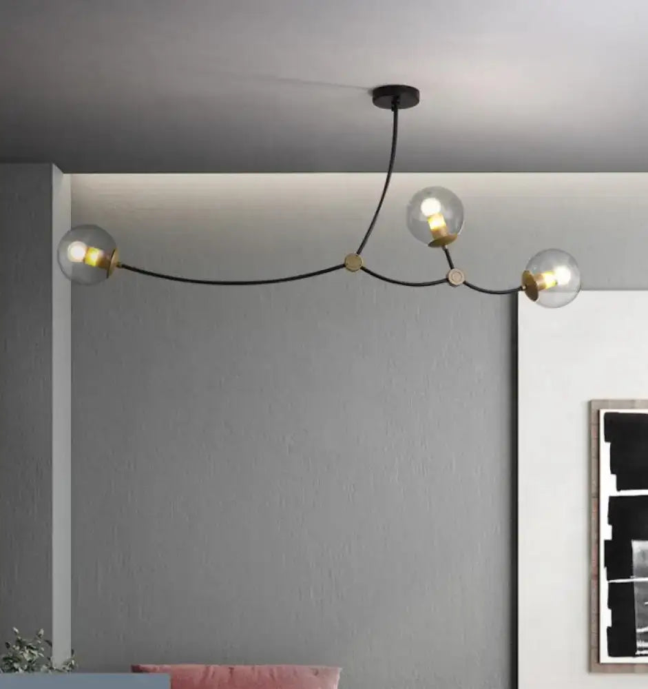 Modern black and gold island light with three clear ball glass shades for dining room use