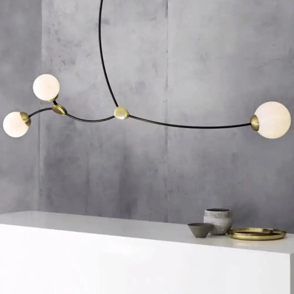 Modern black and gold island light featuring a black metal frame with brass accents and milk white ball glass shade globes
